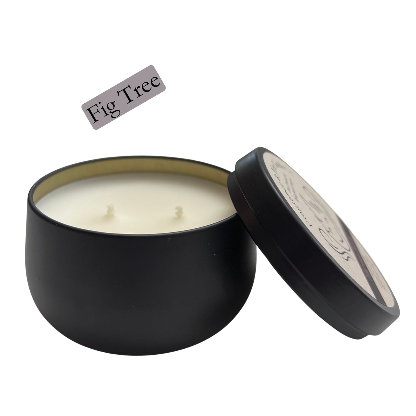 Fragrance & Fire Fig Tree candle. Black container with lid leaning on the side partially showing label with company logo. 2 wicks showing and gold lining of inside the container.