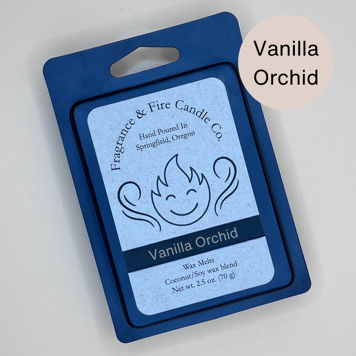 Black clamshell packaging for wax melts from Fragrance & Fire Candle Co., Springfield, Oregon. The packaging features a white label with a stylized flame logo, the text "Fragrance & Fire Candle Co. Hand Poured In Springfield, Oregon," and "Vanilla Orchid" scent name. The label also includes the text "Wax Melts Coconut/Soy wax blend Net wt. 2.5 oz. (70 g)." An eggshell circle in the upper right corner says scent name.