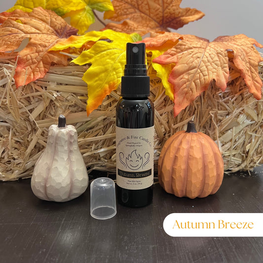 Fragrance & Fire Autumn Breeze  fragrance mist in a sleek black bottle with a brown label featuring the company name and logo, displayed with cozy fall decor including pumpkins and leaves.