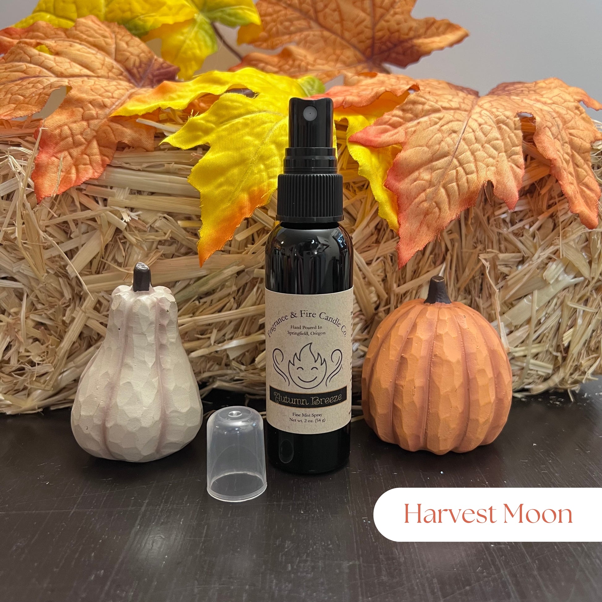 Fragrance & Fire Harvest Moon Fragrance Mist in a sleek black bottle with a brown label featuring the company name, displayed with cozy fall decor including pumpkins and leaves.