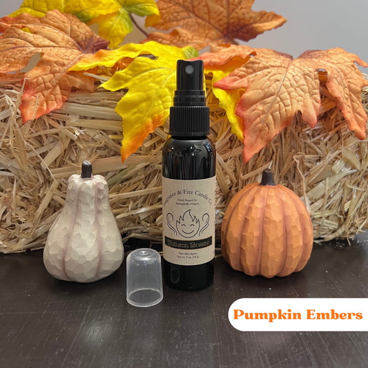 Fragrance & Fire Pumpkin Embers Fragrance Mist in a sleek black bottle with a brown label featuring the company name, displayed with cozy fall decor including pumpkins and leaves.