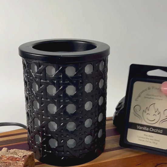 Video showcasing Wax Melts being opened, a wax cube placed into an electric wax melter, and the melter being turned on. The melter sits on a wooden board surrounded by rocks with a white background. The Fragrance & Fire Candle Co. logo and name appear at the end.